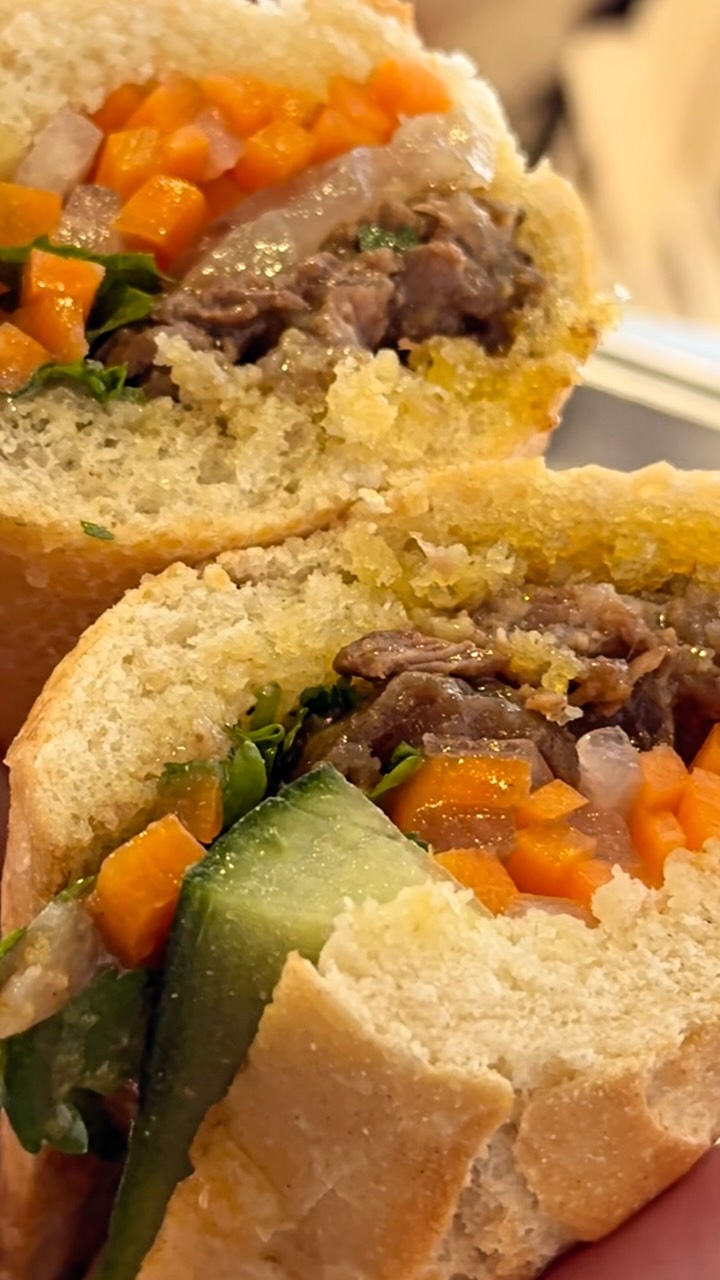A bánh mì cut open: slow-cooked beef, pickled carrot, cucumber and herbs