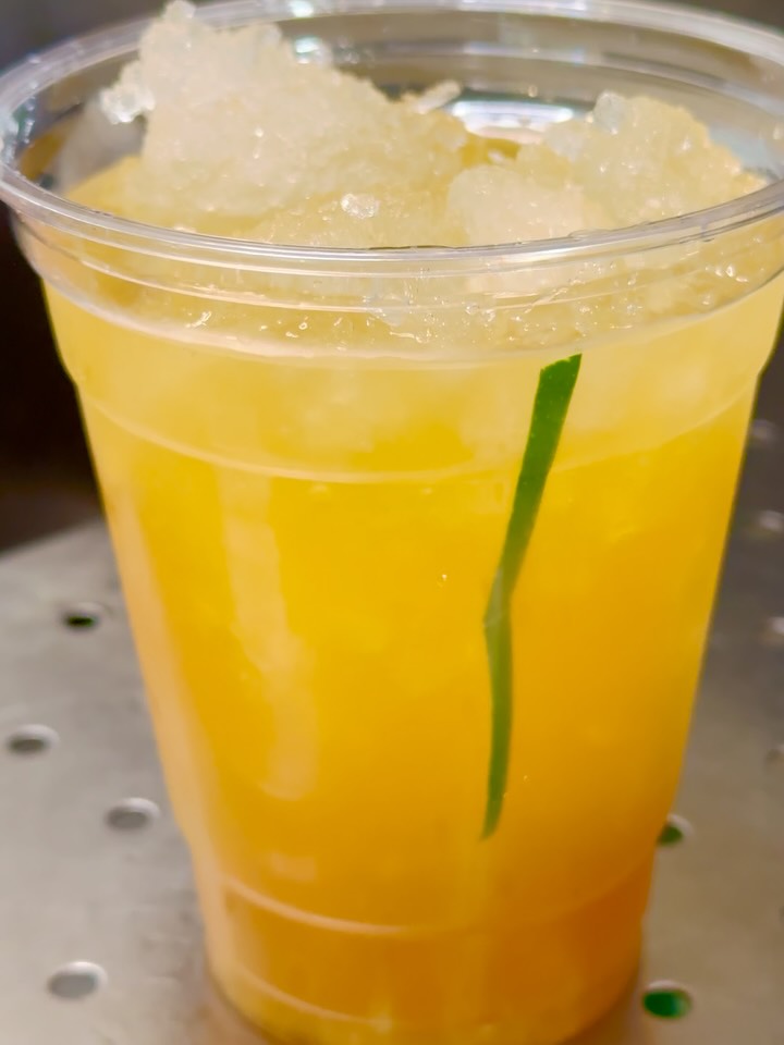 An iced drink with crushed ice and a green straw